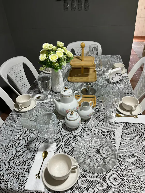 Mesa ángel: mantel de encaje, juego de té floreado con detalles dorados, rosas blancas y posatortas de bambú