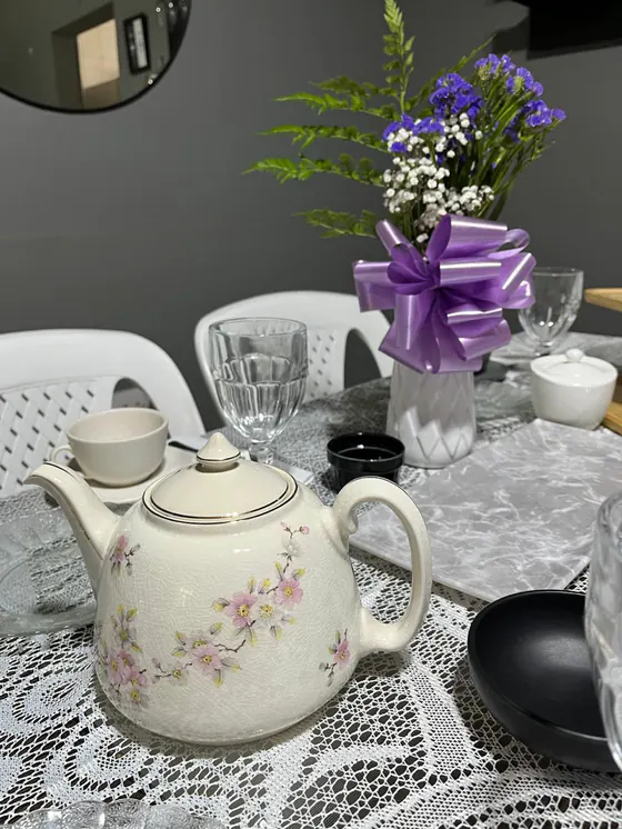 Tetera crema con flores de cerezo y florero con moño lila