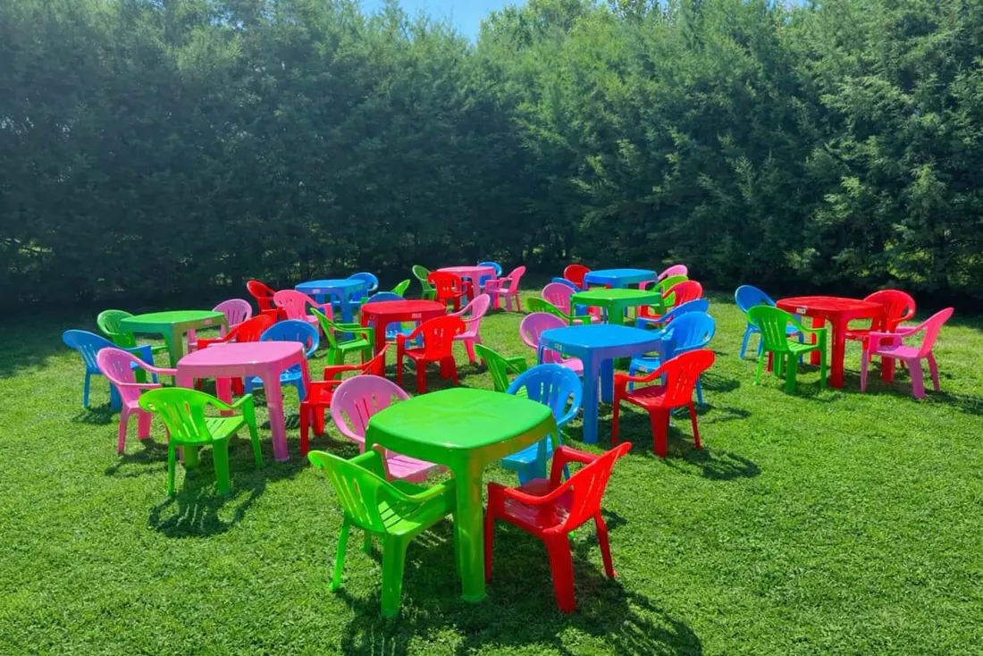 Mesitas y sillitas de colores para chicos, armadas sobre el pasto